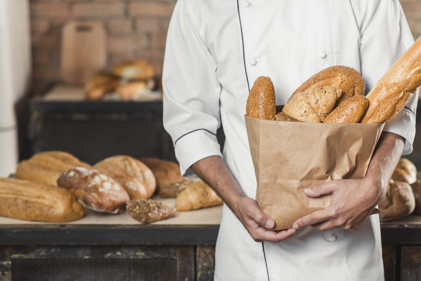 Un boulanger tient un sac kraft rempli de pains