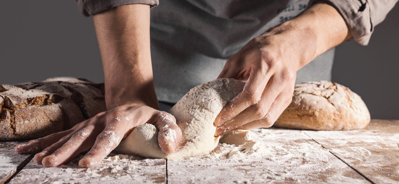 Des mains qui travaillent la pâte sur le plan fariné